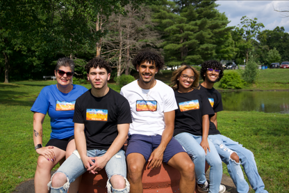three men and 2 women siting altogether wearing blue, white, and black keep moving tees